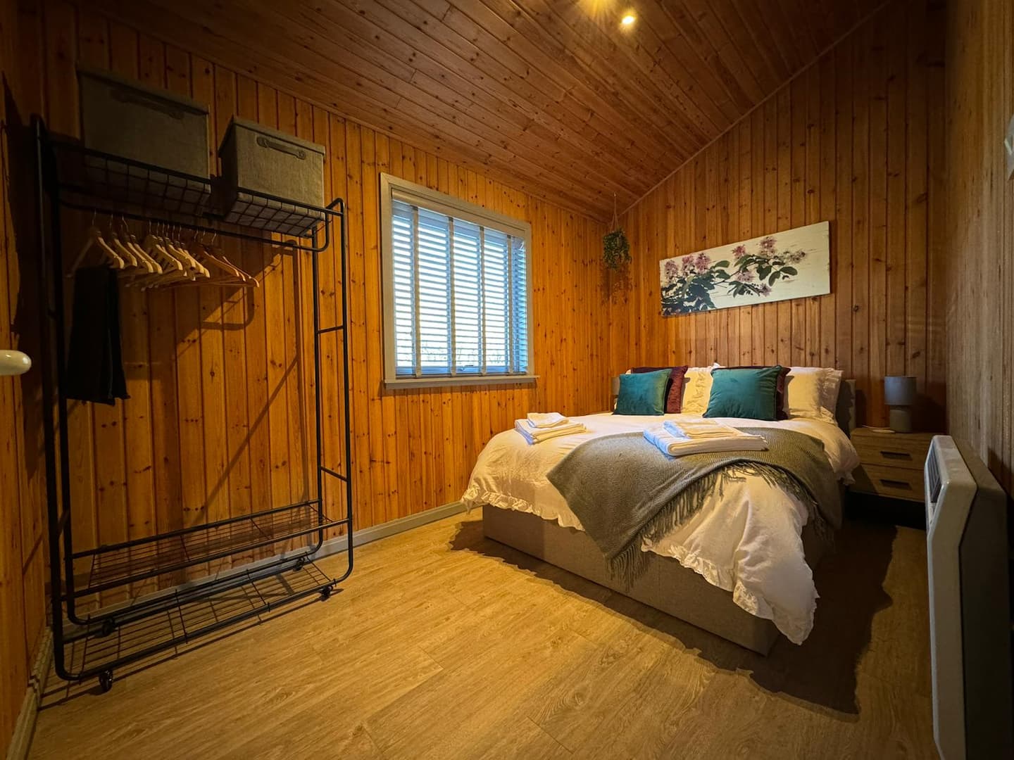 Comfortable double bedroom with pine walls and made bed